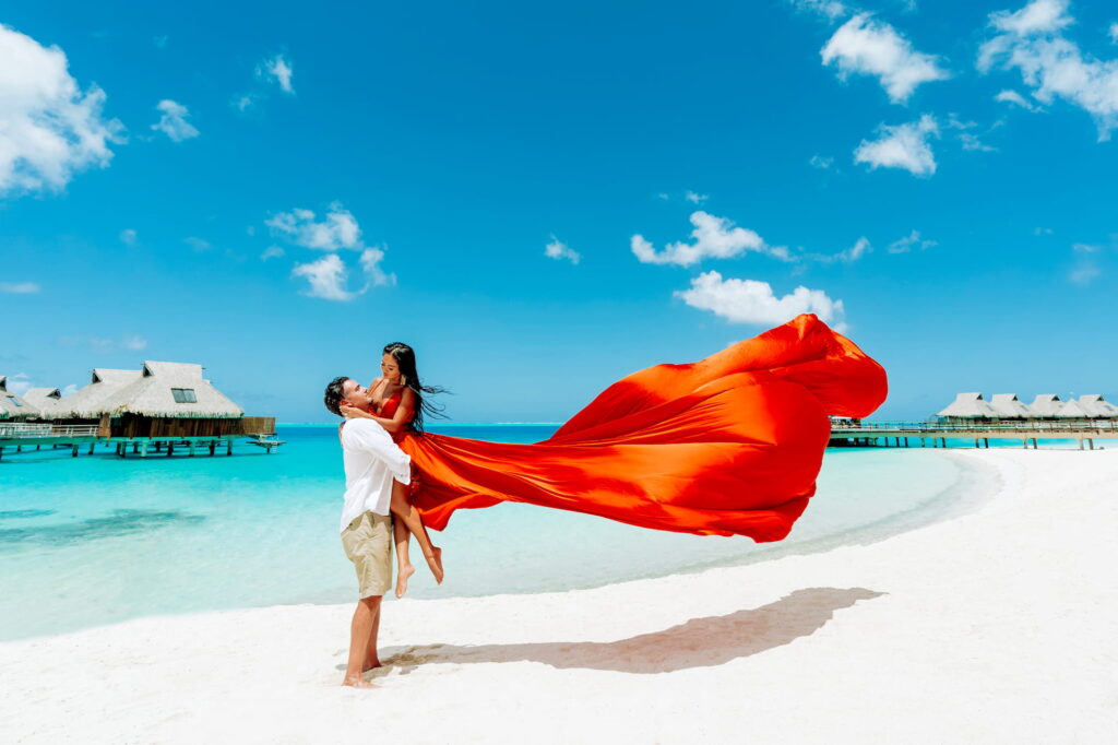 photo d'un couple sur la plage avec une flying dress rouge.